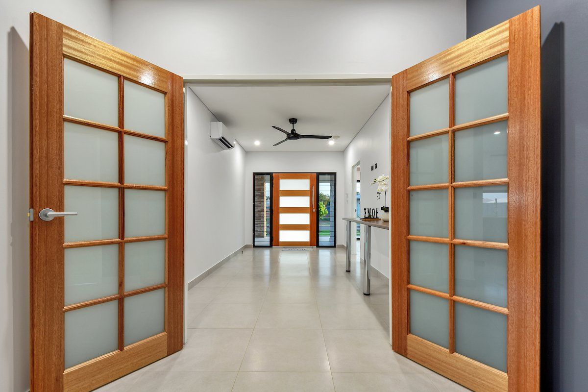 A hallway with two wooden doors and a ceiling fan.