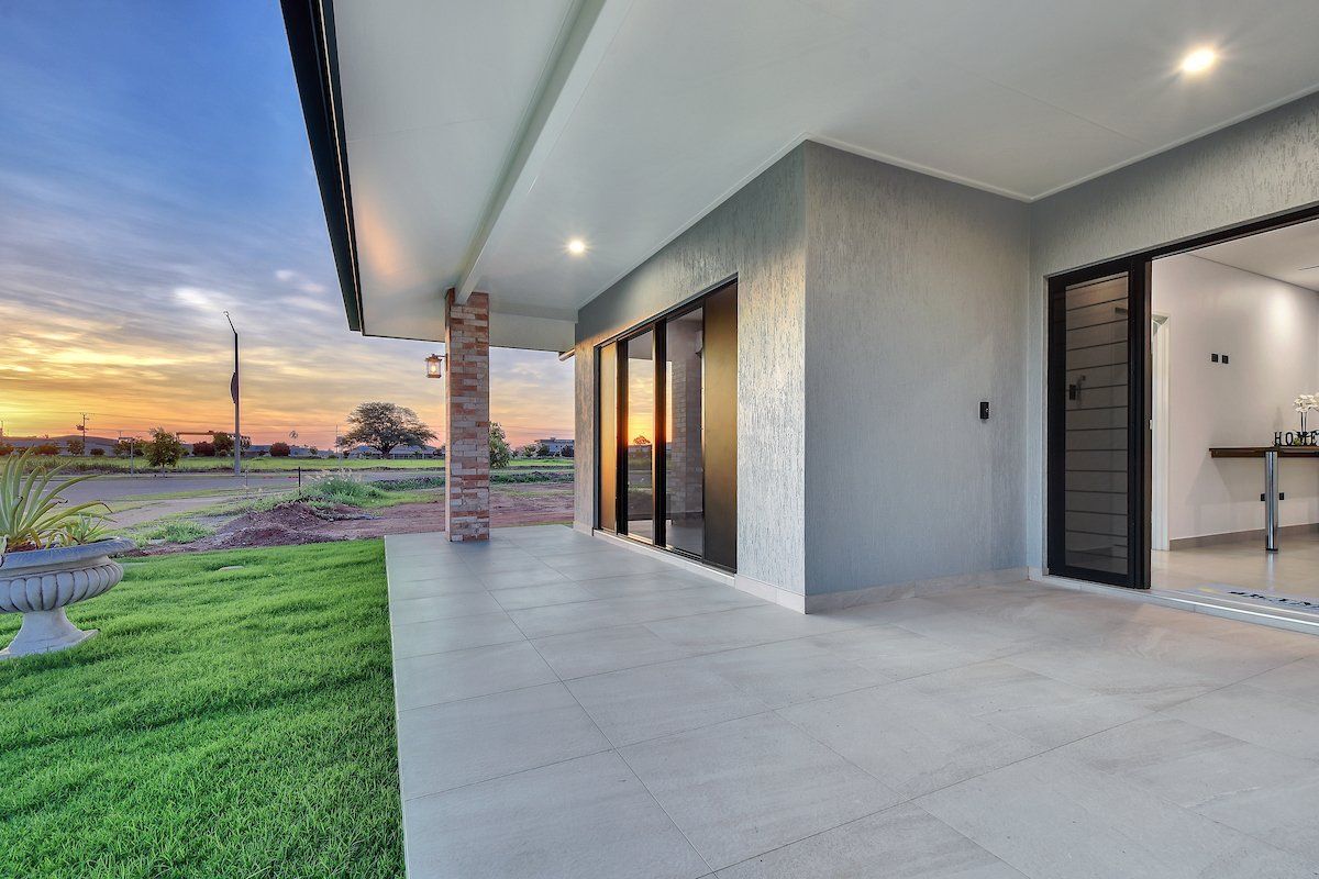 A large patio with a sliding glass door and a sunset in the background.