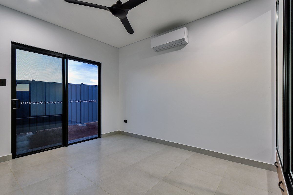 An empty room with a ceiling fan and sliding glass doors.