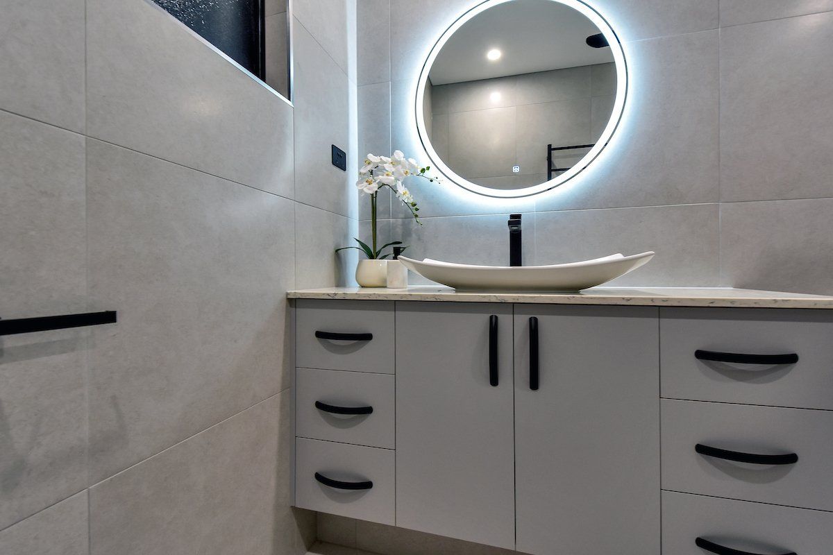 A bathroom with a sink , mirror and drawers.