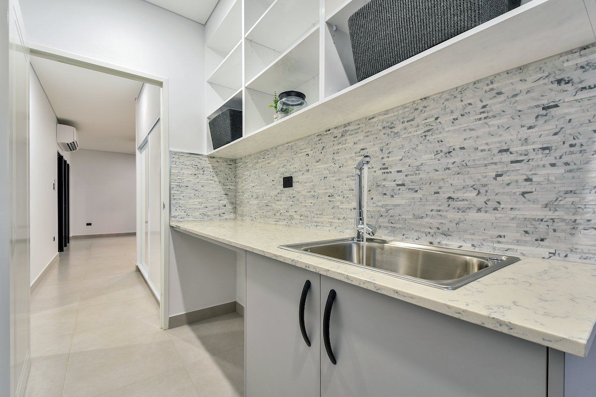 A kitchen with a sink , cabinets and shelves.