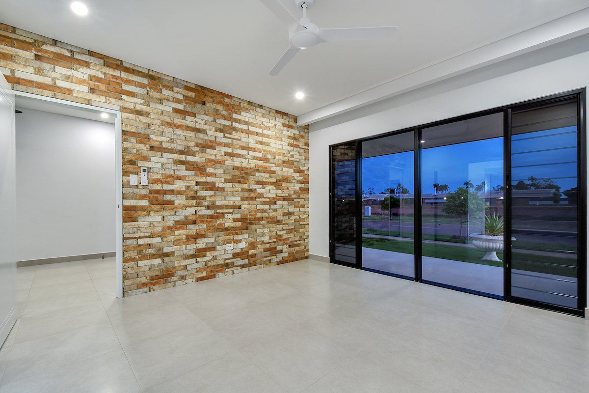 An empty living room with a brick wall and sliding glass doors.