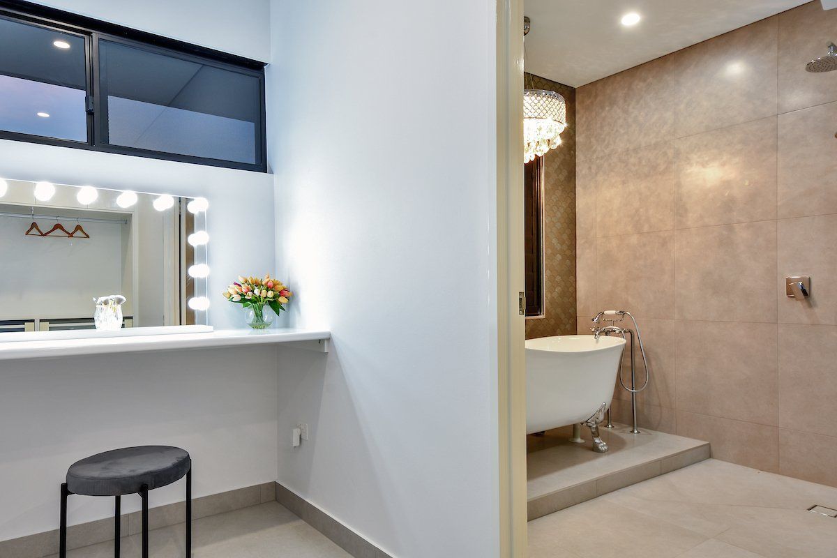 A bathroom with a tub and a vanity with lights on it.