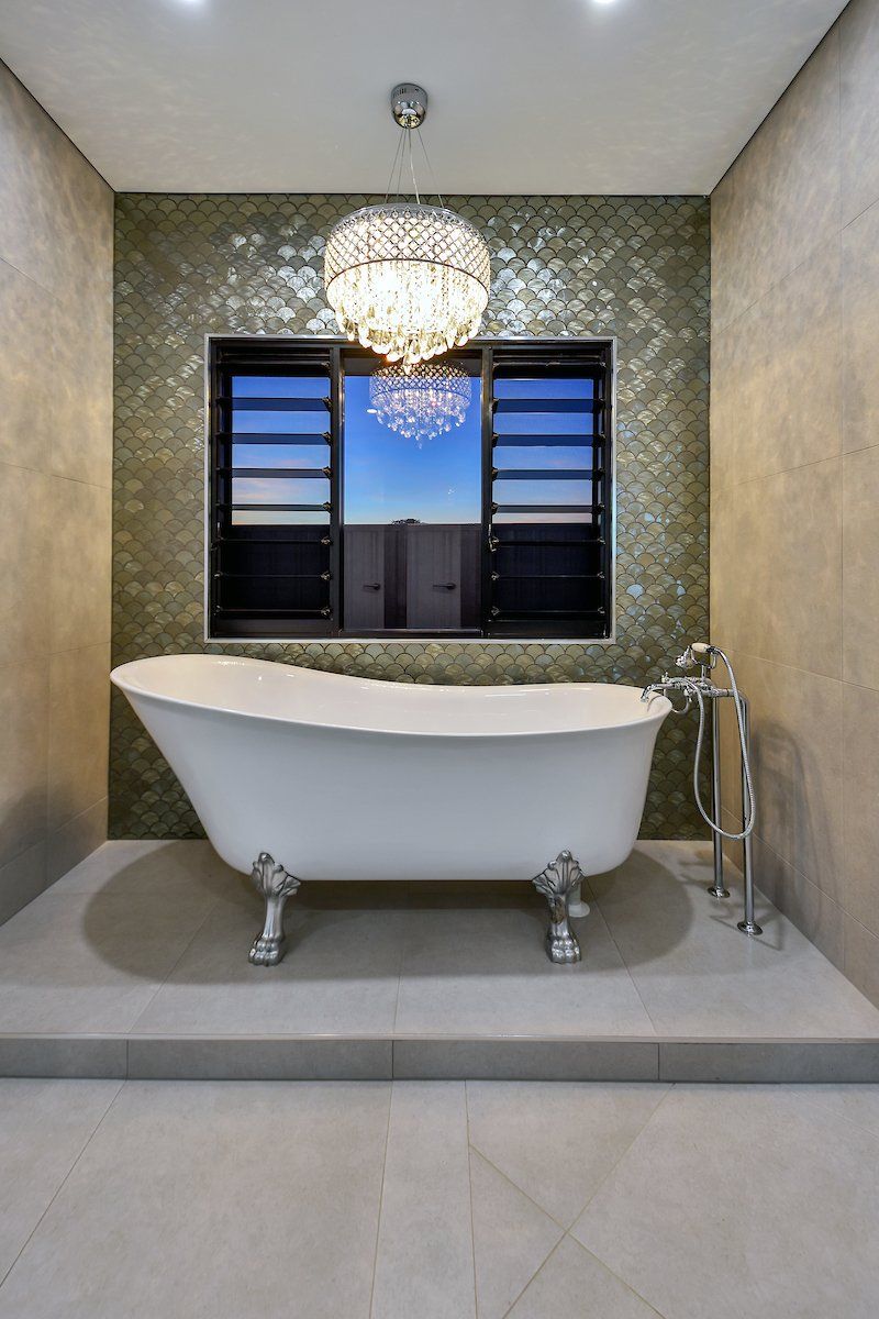 A bathroom with a bathtub and a window with a chandelier hanging from the ceiling.