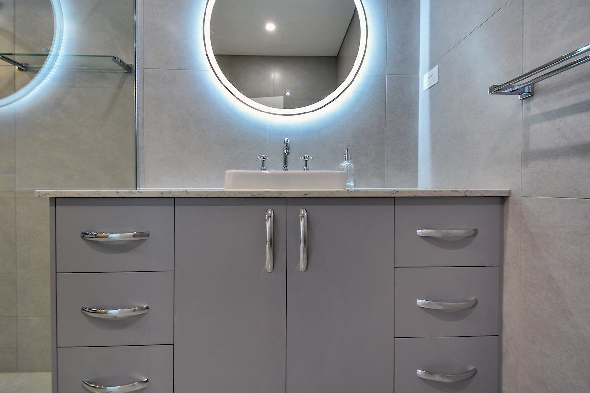 A bathroom with a sink and a round mirror