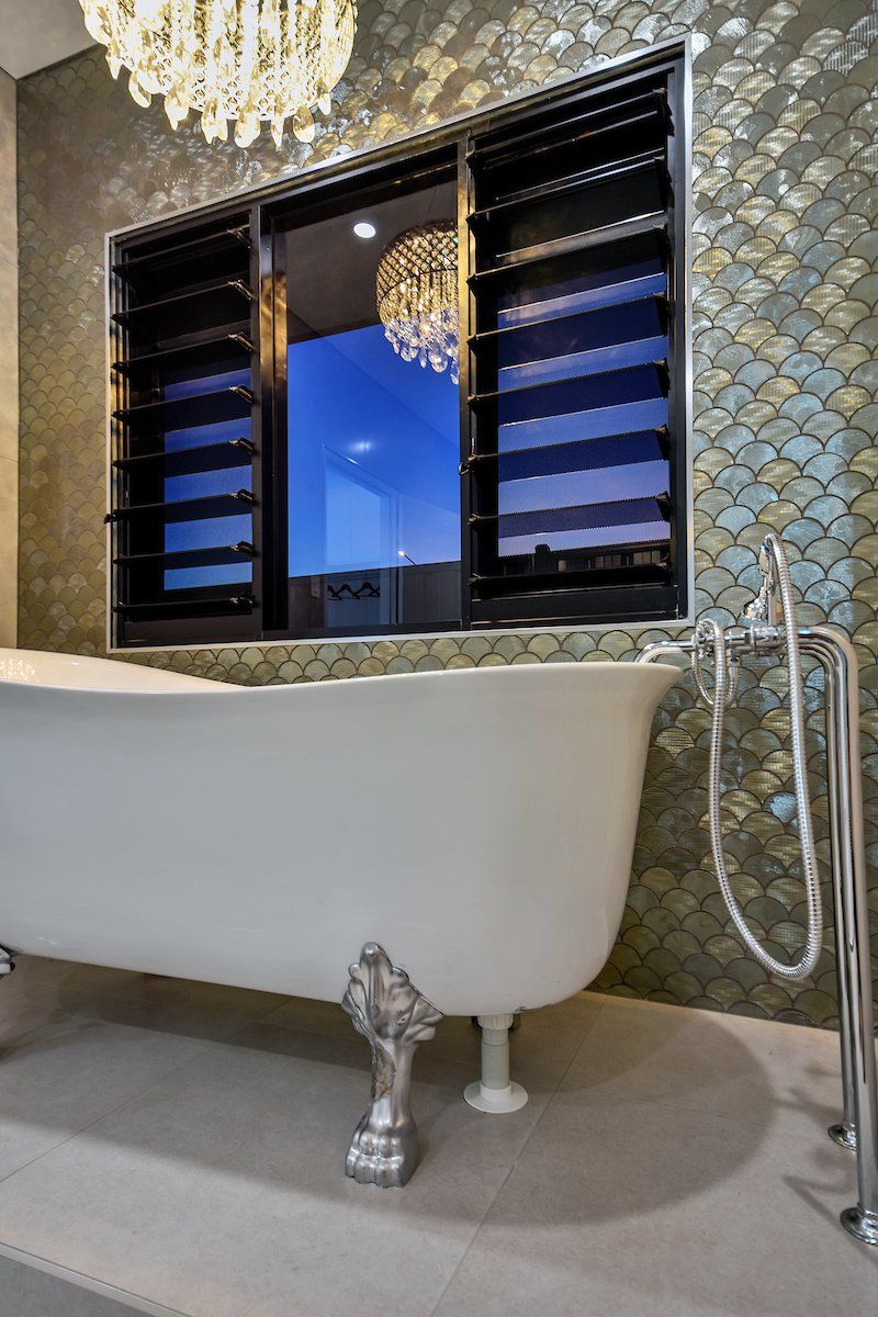A bathtub in a bathroom with a window and a chandelier.