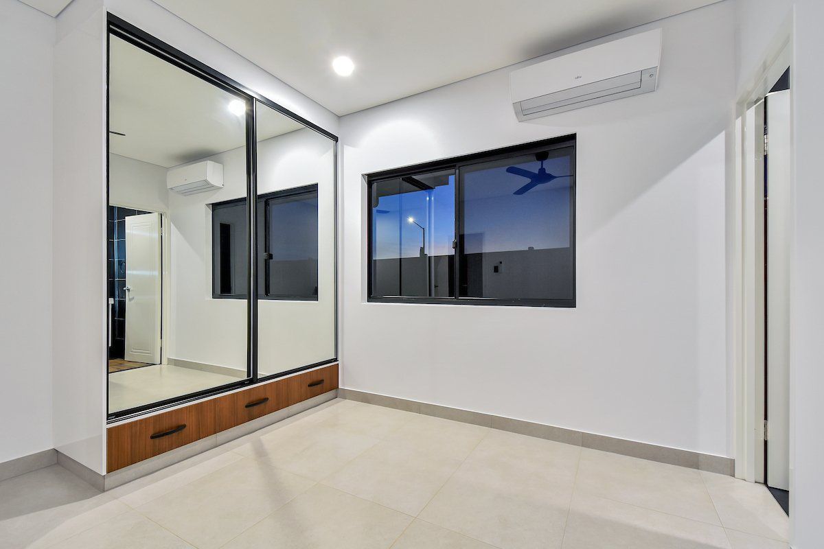 An empty room with a sliding glass door and two windows.