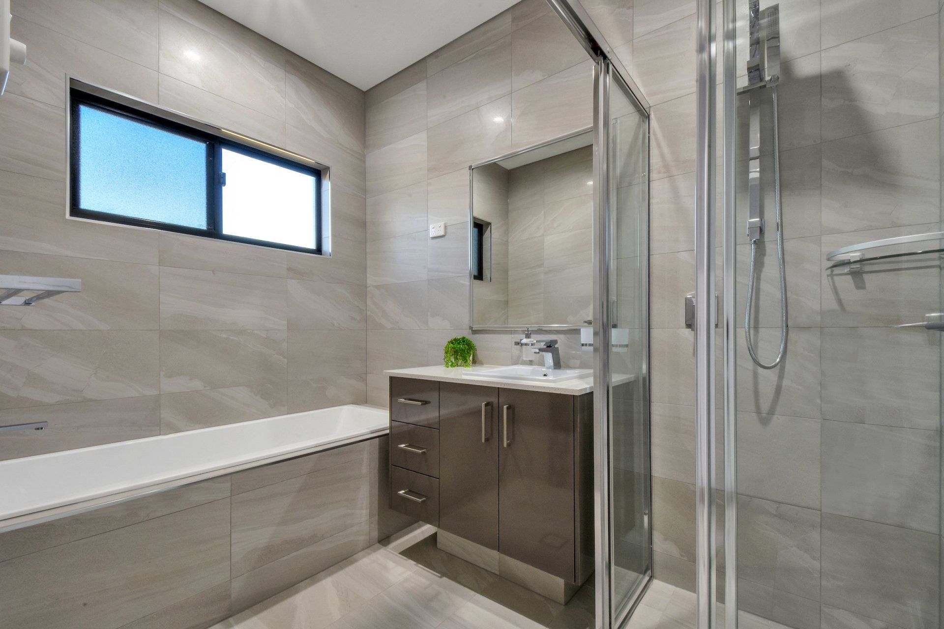 A bathroom with a tub , sink , mirror and shower.