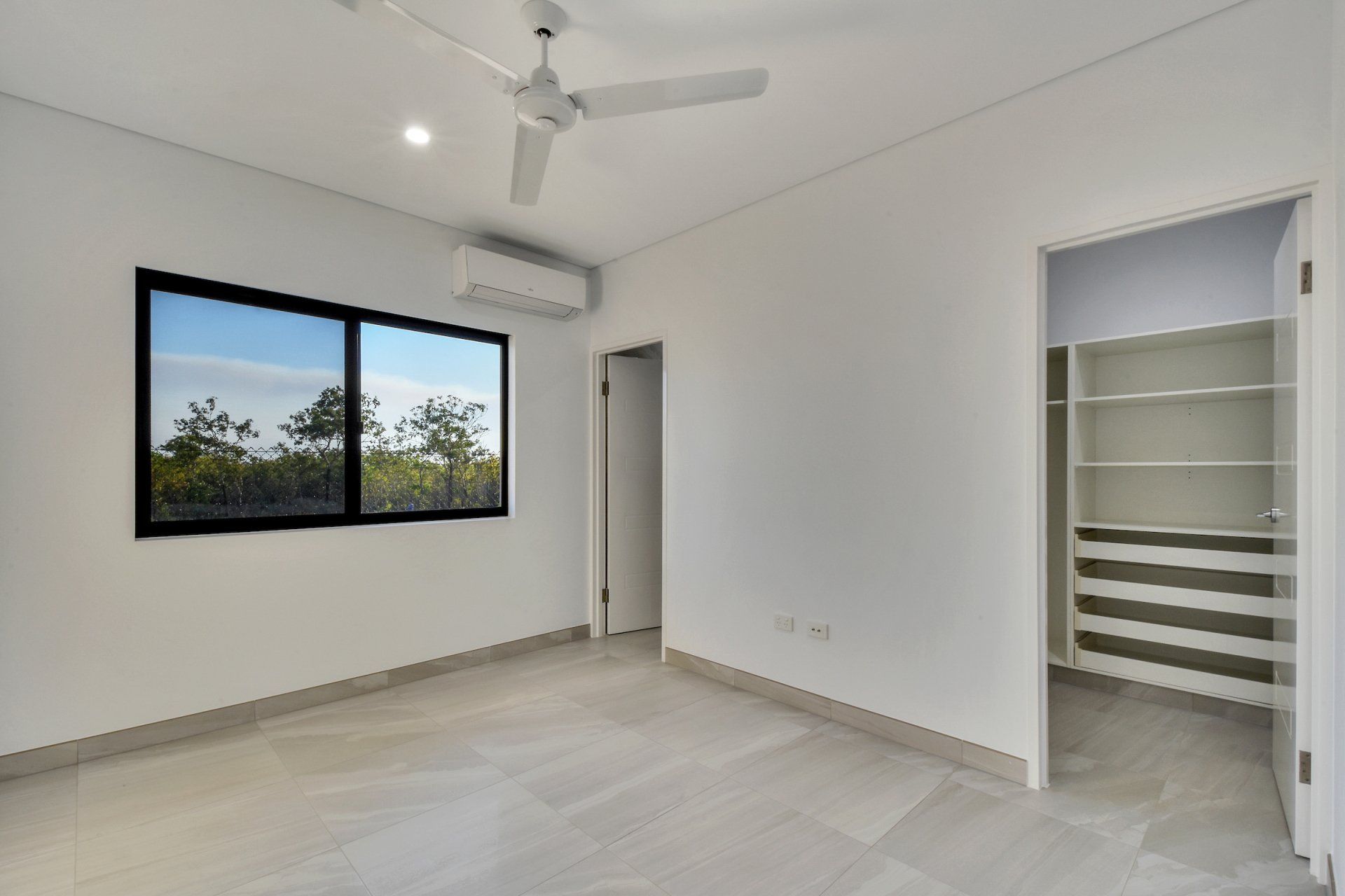 An empty bedroom with a ceiling fan and a walk in closet.