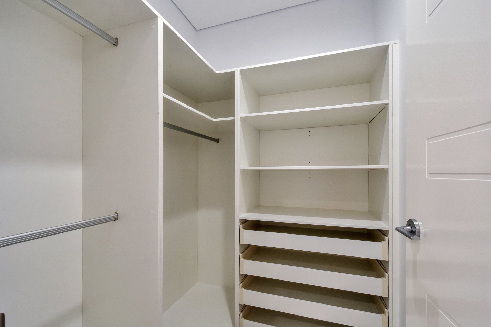 A walk in closet with lots of shelves and drawers.