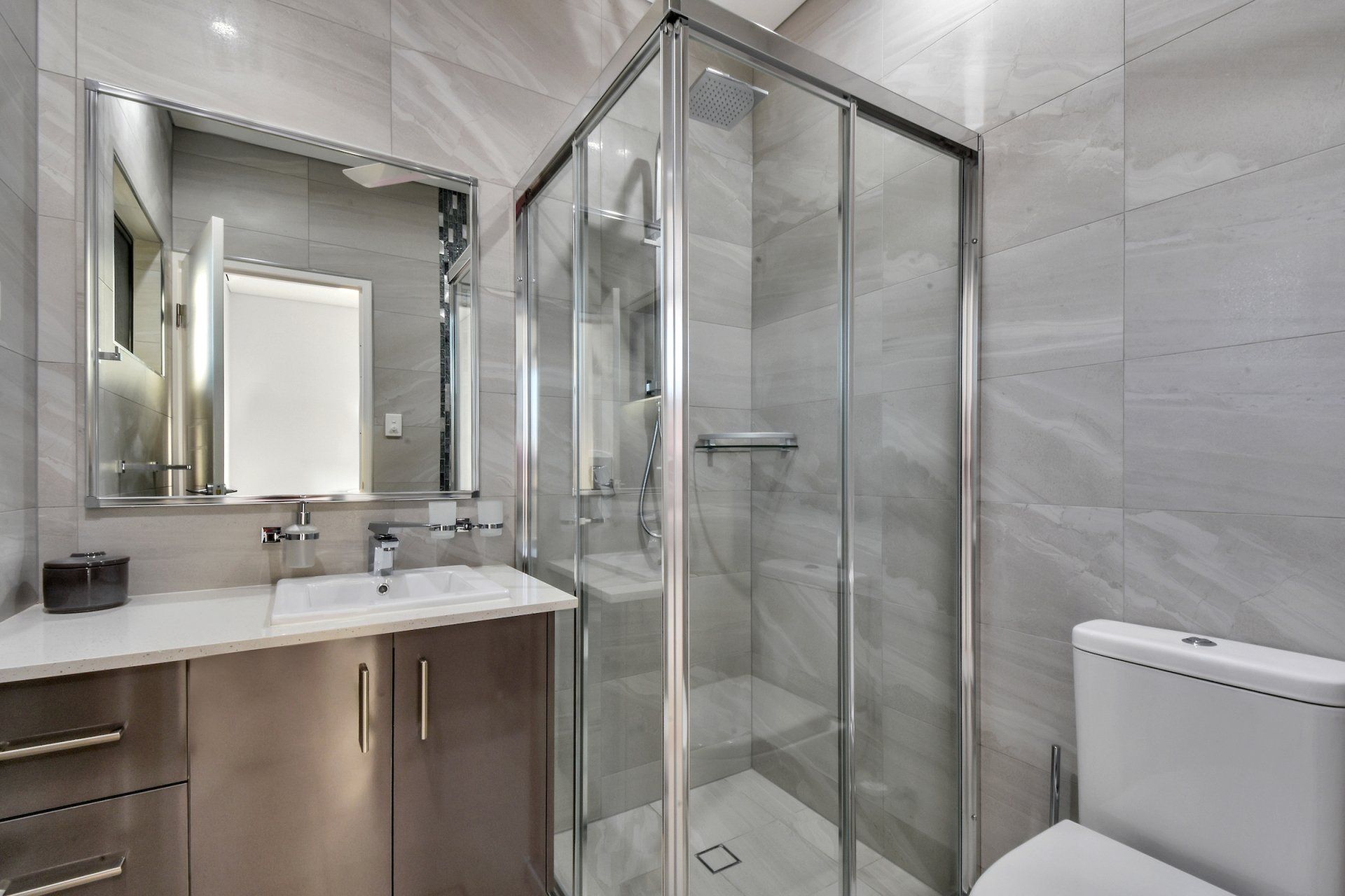 A bathroom with a toilet , sink , mirror and shower stall.