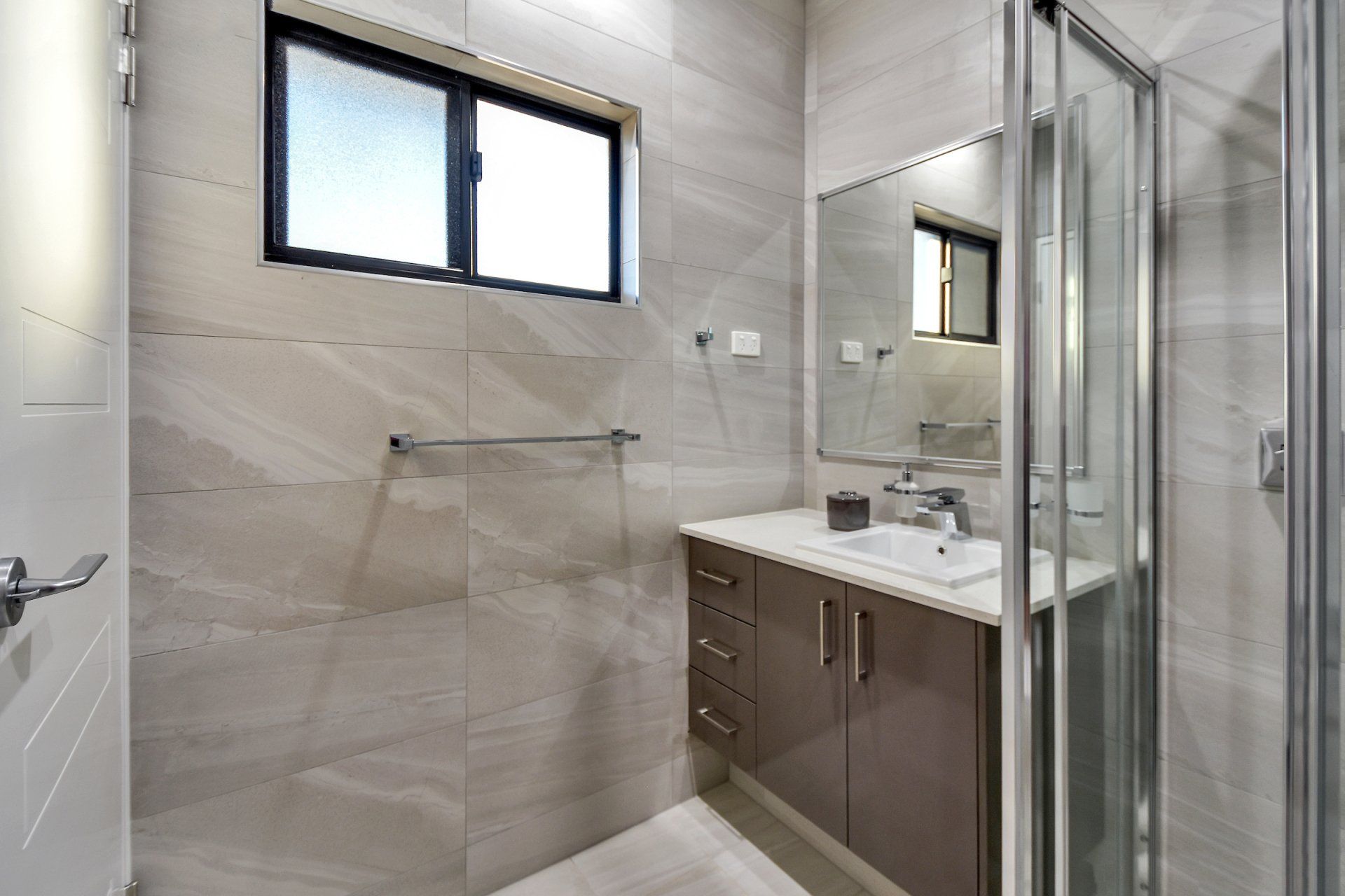 A bathroom with a sink , mirror and shower stall.
