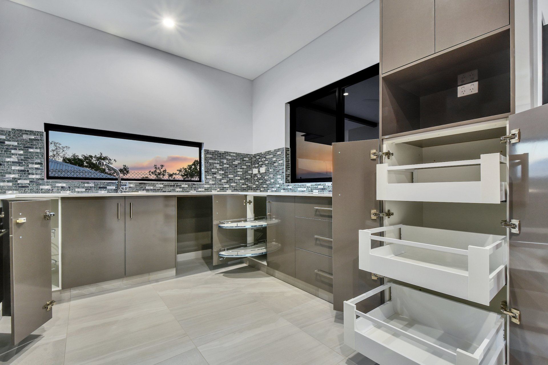 A kitchen with a lot of cabinets and drawers and a window.