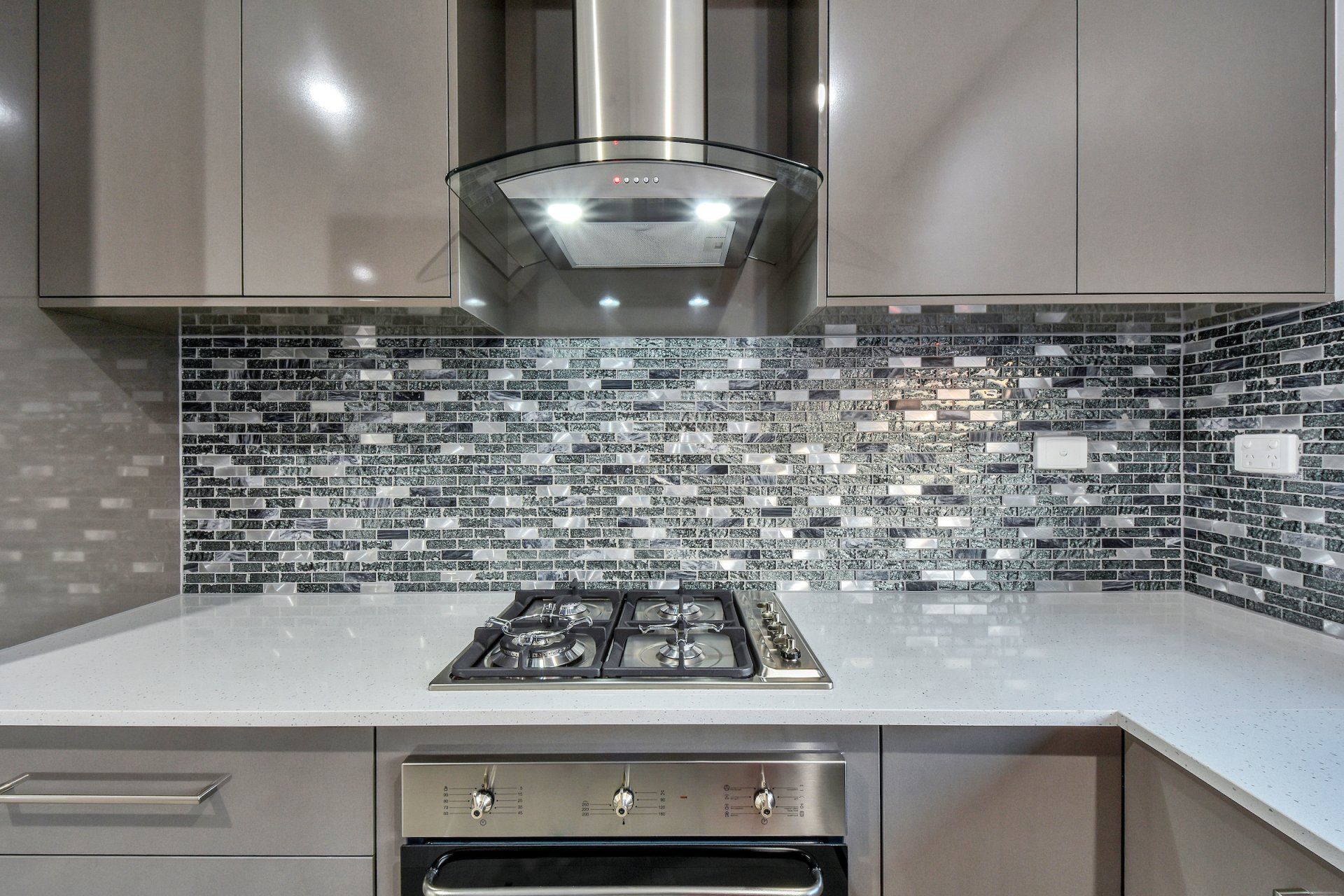 A kitchen with a stove top oven and a hood.