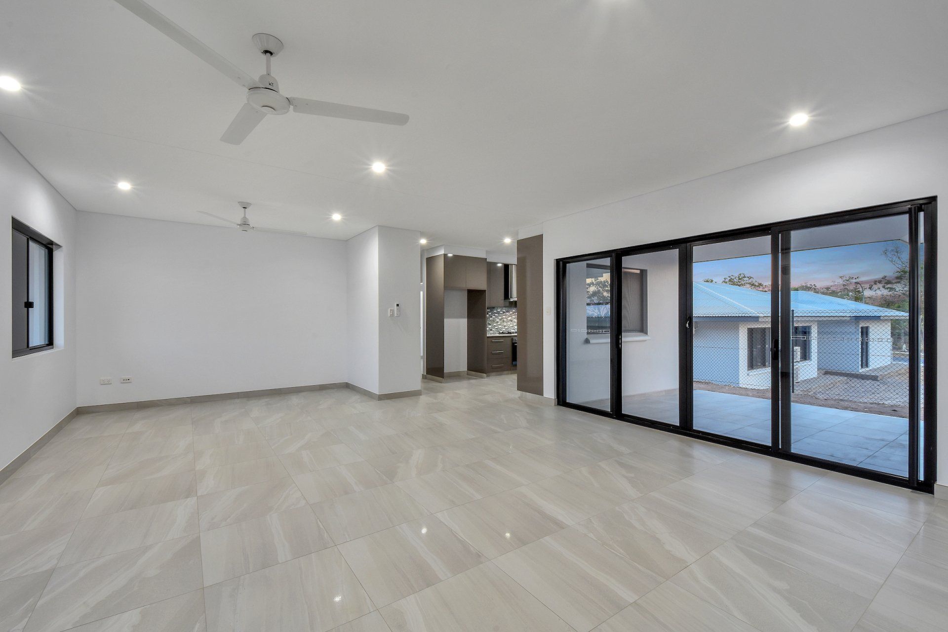An empty living room with sliding glass doors and a ceiling fan.