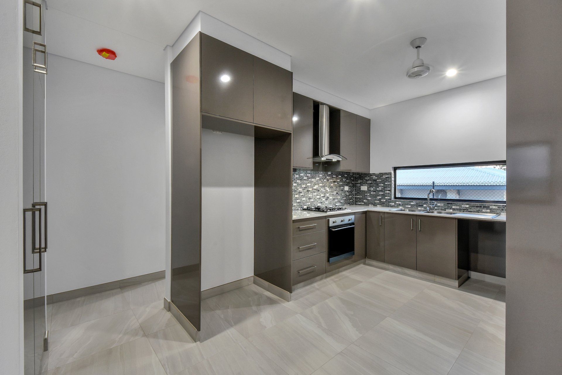 A kitchen with brown cabinets , a stove , a refrigerator and a window.