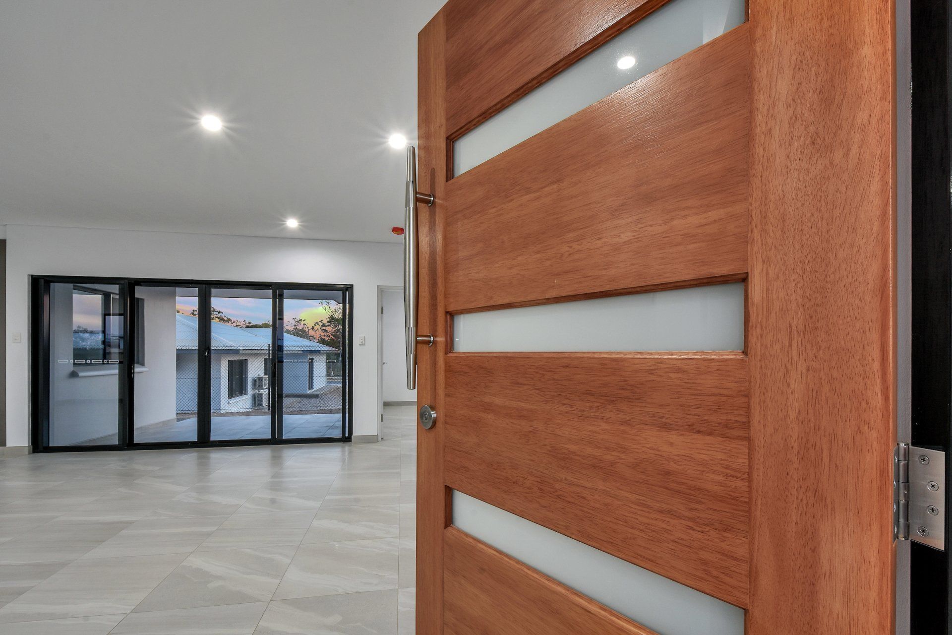 A wooden door is open to an empty room with sliding glass doors.