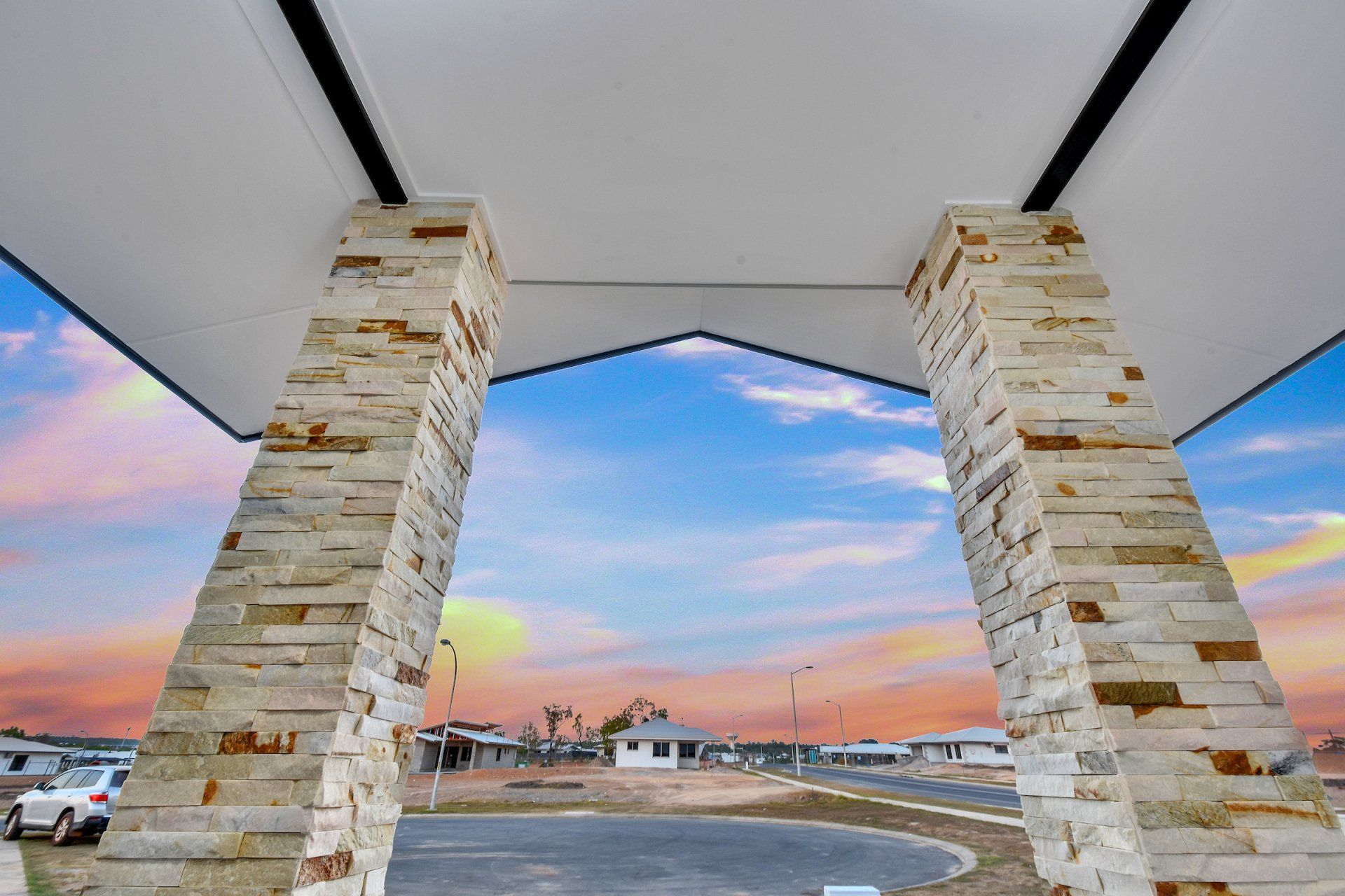 A view of a parking lot through a stone archway.