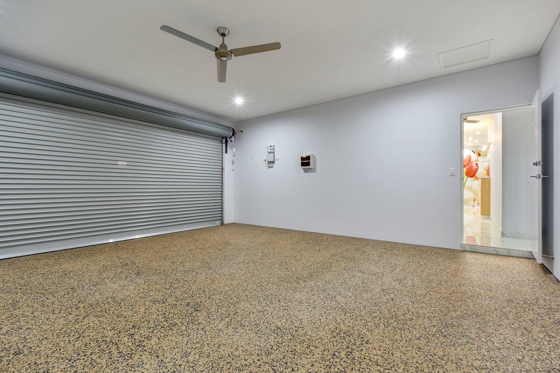 An empty garage with a ceiling fan and a garage door.