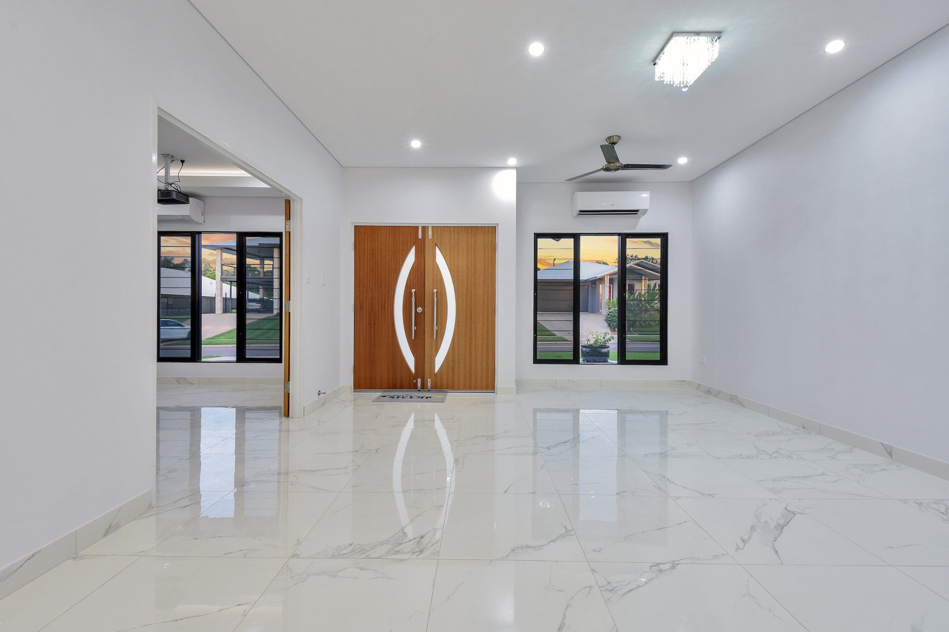 A large empty room with a marble floor and a wooden door.