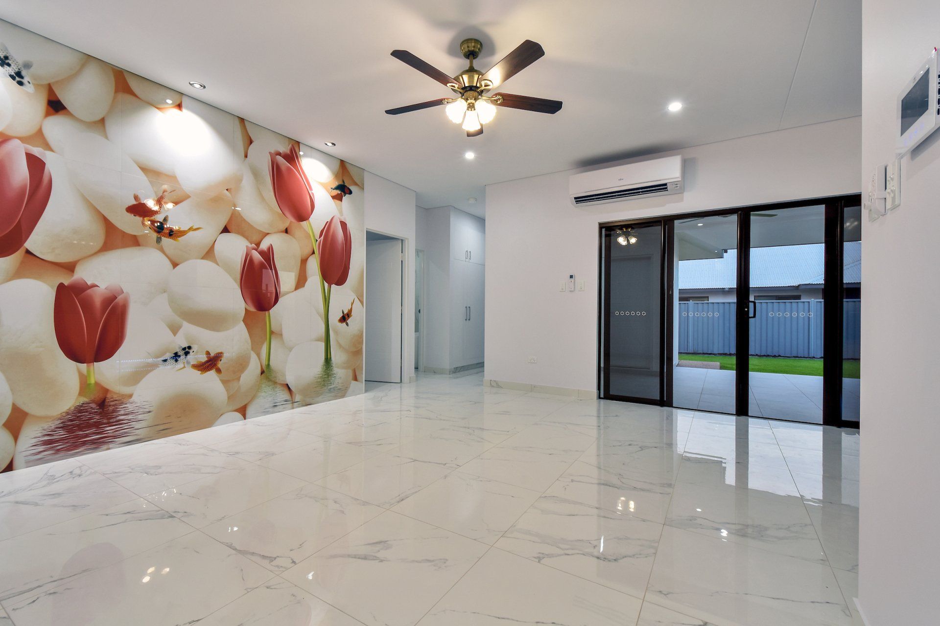 An empty living room with a ceiling fan and a picture of flowers on the wall