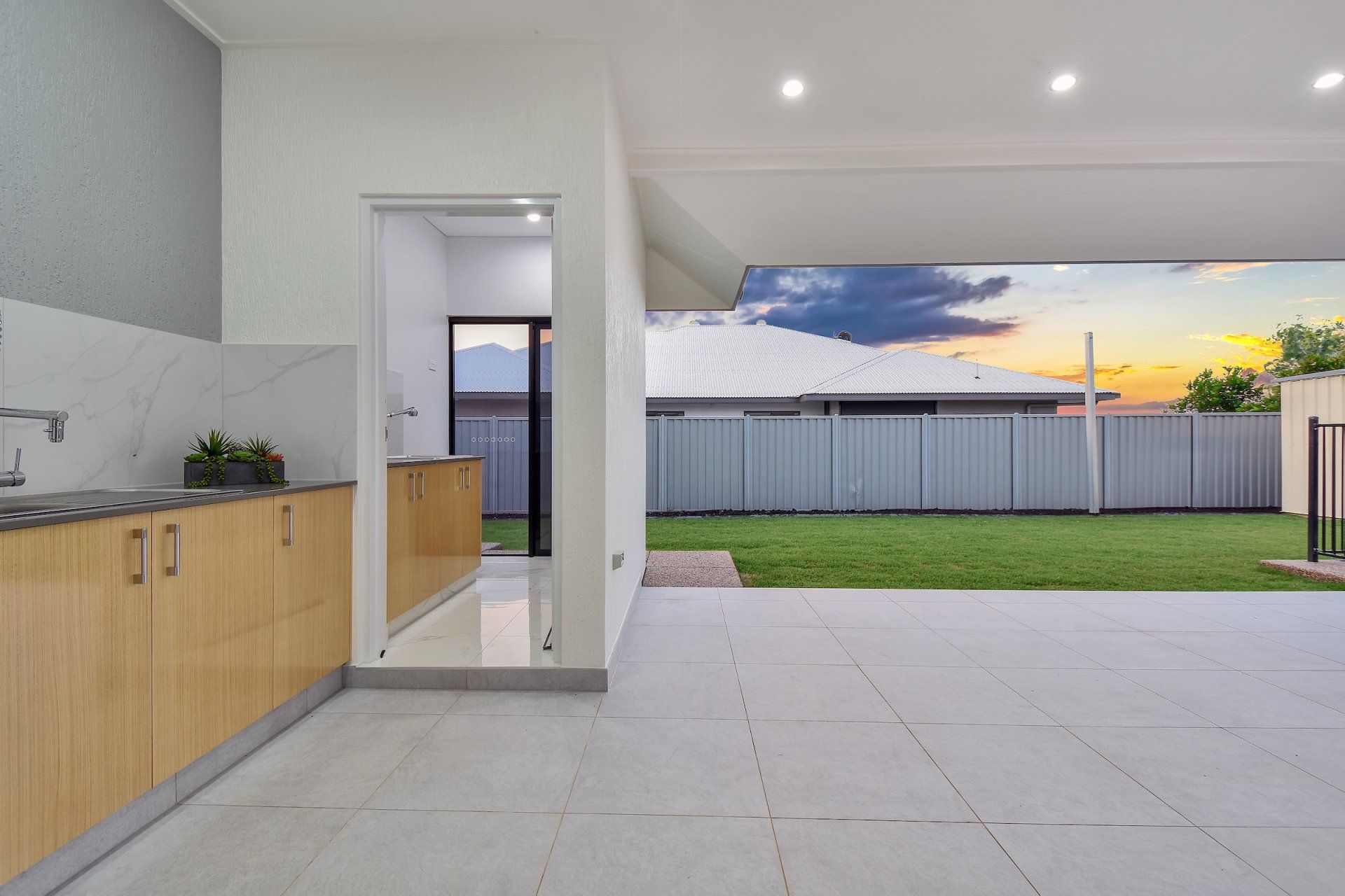 A kitchen with a patio and a fence in the background.