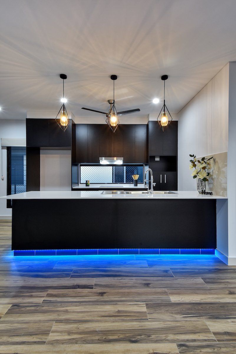 A kitchen with a large island and blue lights underneath it.