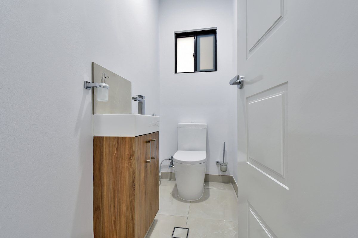 A bathroom with a toilet , sink and window