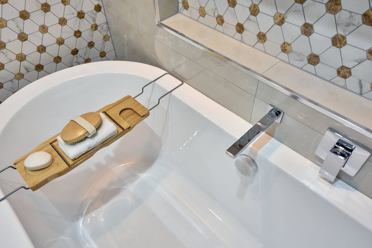 A bathtub with a wooden tray on top of it in a bathroom.