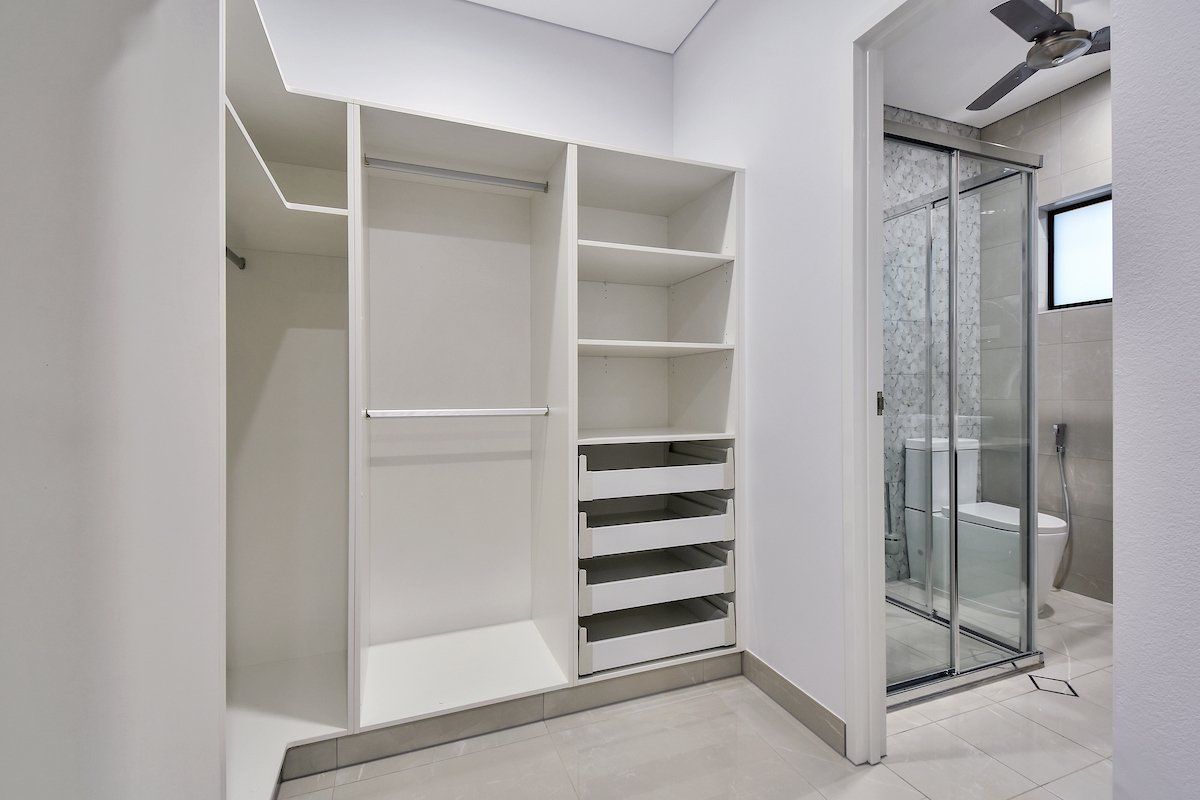 A walk in closet with lots of shelves and drawers next to a bathroom.