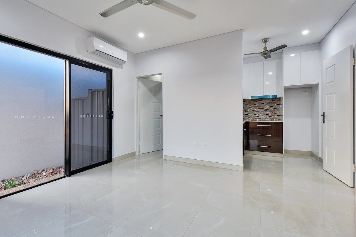 An empty room with a ceiling fan and a sliding glass door.