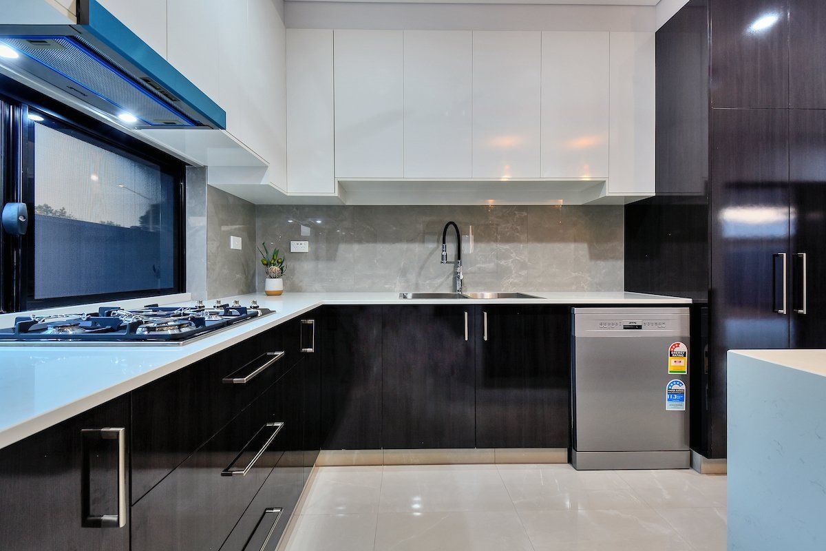 A kitchen with black and white cabinets and a stainless steel dishwasher
