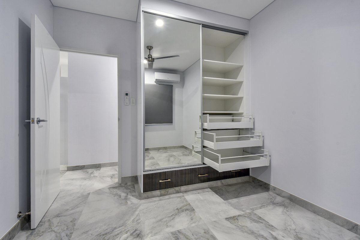 A bedroom with a large wardrobe and a ceiling fan.
