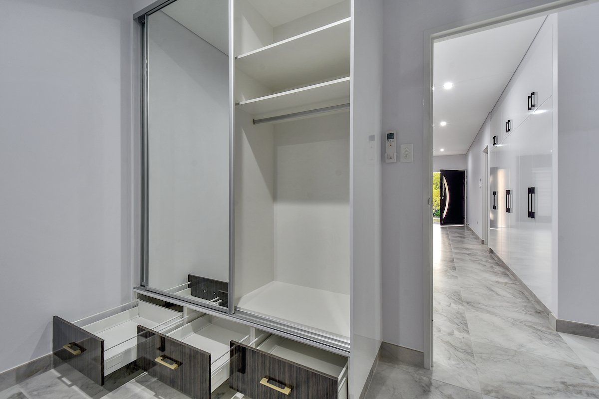 An empty closet with drawers and a mirror in a hallway.