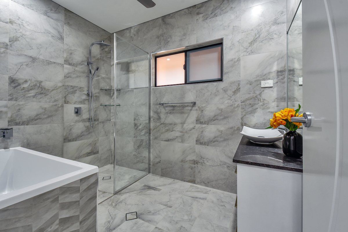 A bathroom with a bathtub , sink , shower and window.