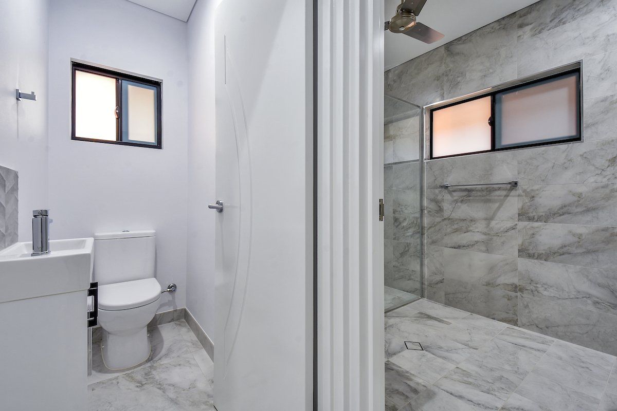 A bathroom with a toilet , sink and shower.
