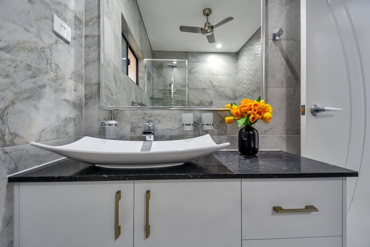 A bathroom with a sink and a vase of flowers on the counter.