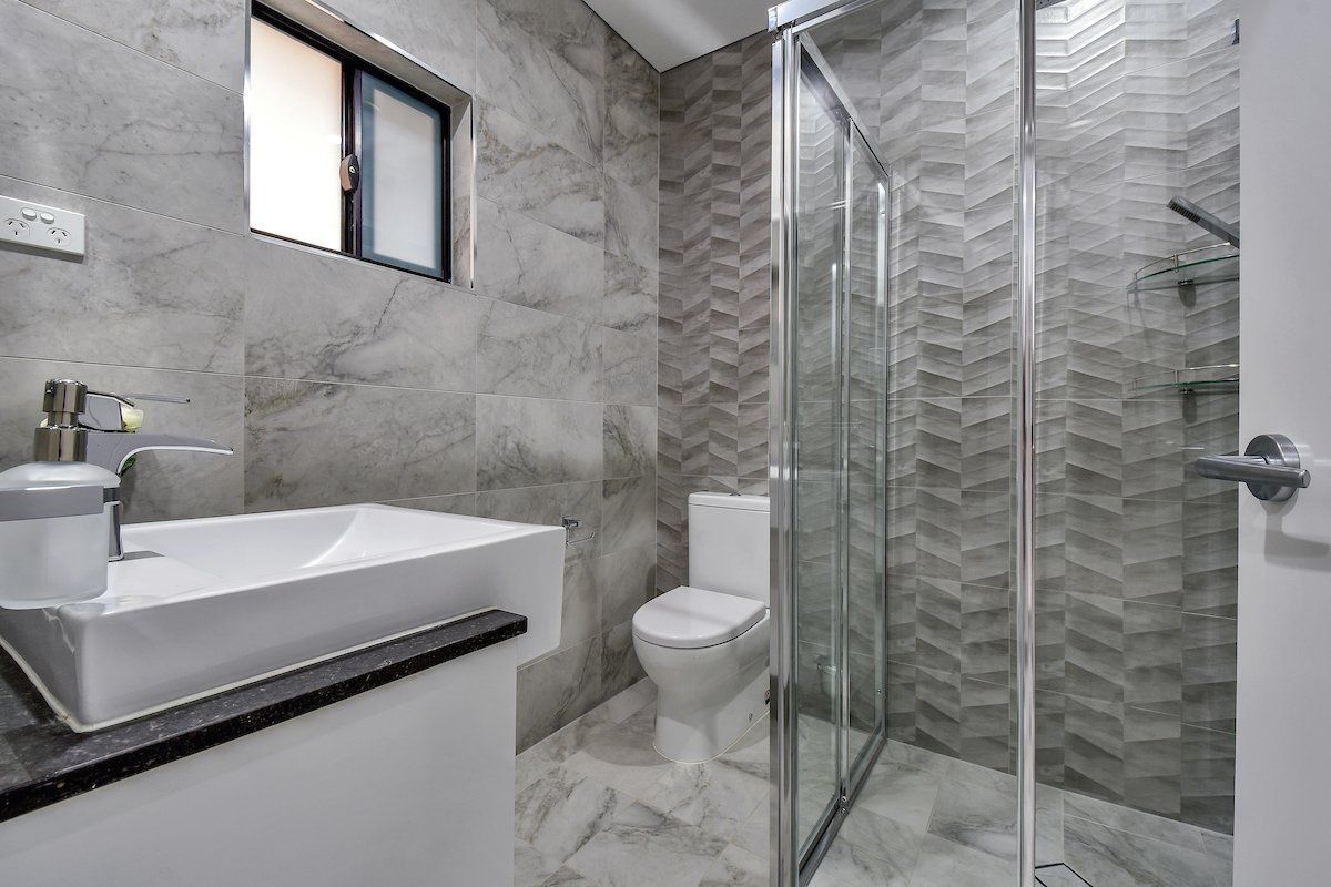 A bathroom with a toilet , sink , and shower.