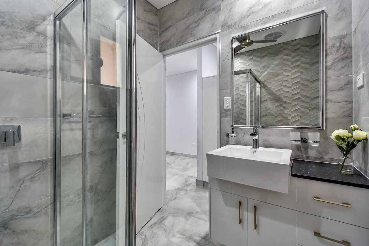 A bathroom with a sink , mirror and walk in shower.