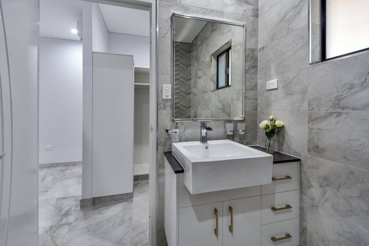 A bathroom with a sink , mirror and drawers.