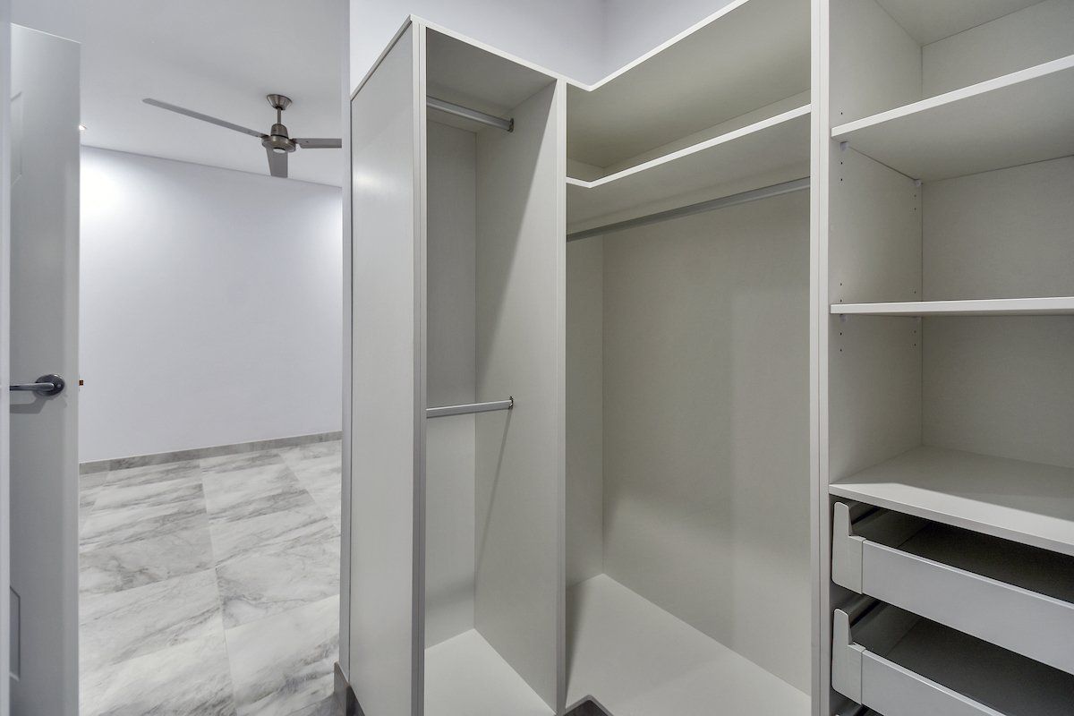 A walk in closet with a ceiling fan in a bedroom.