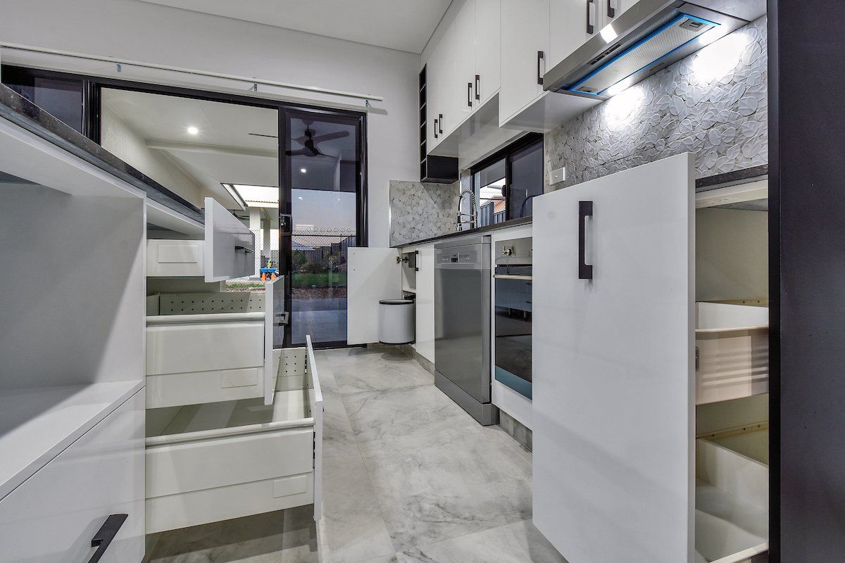 A kitchen with white cabinets and drawers and a sliding glass door.