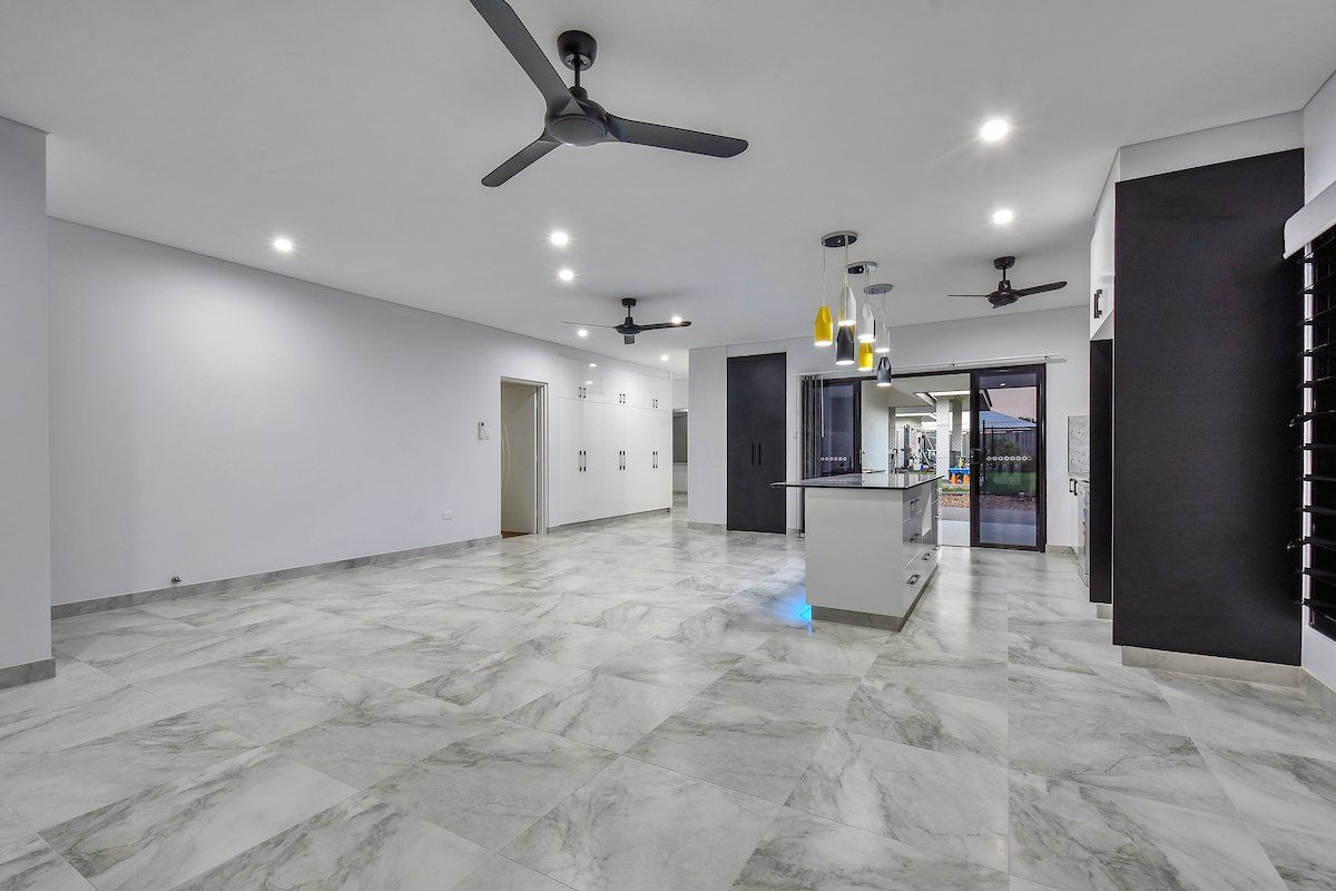 A large empty room with a ceiling fan hanging from the ceiling.