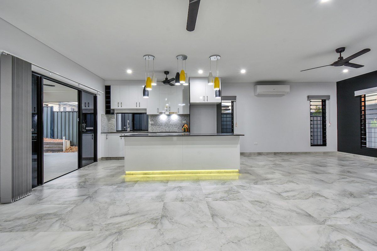 An empty room with a kitchen and a ceiling fan