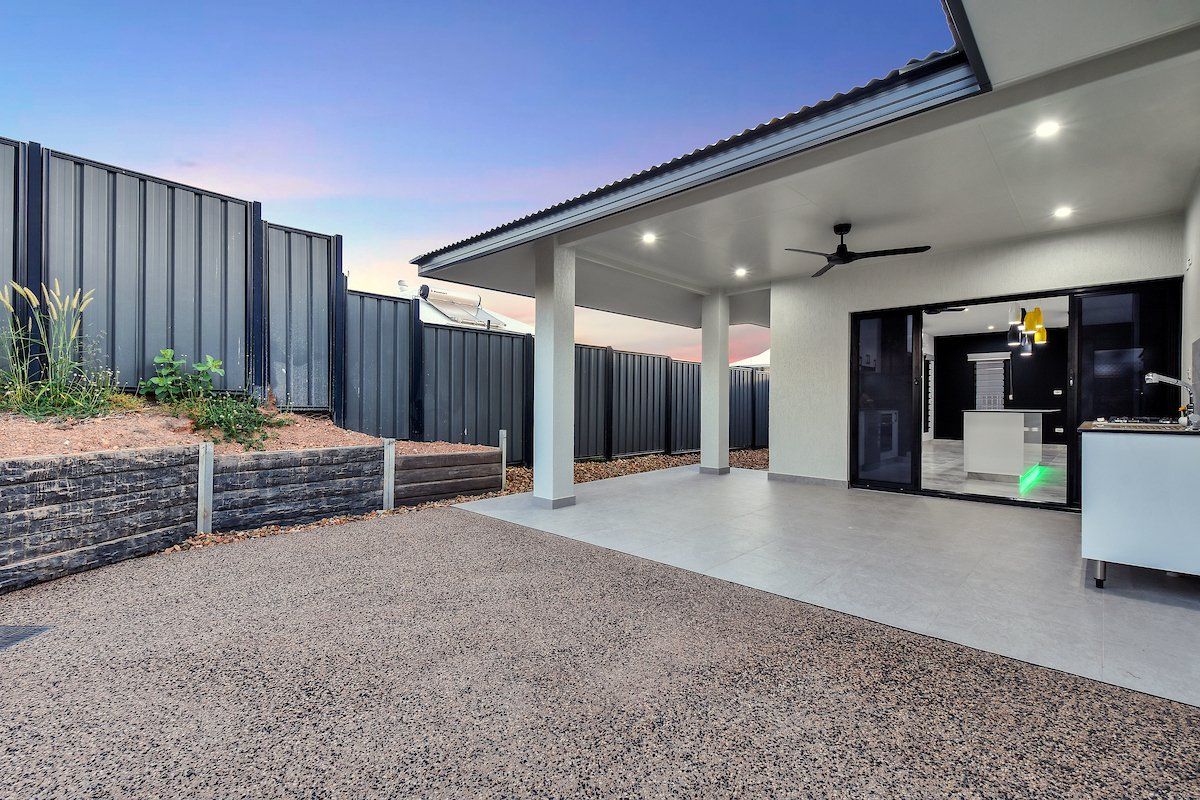 The backyard of a house with a covered patio and a ceiling fan.