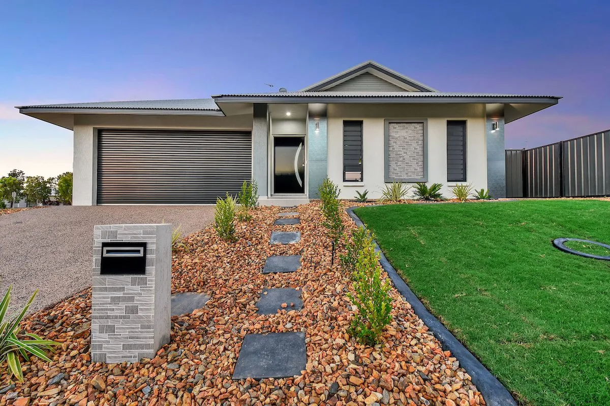 A white house with a black garage door is sitting on top of a lush green lawn.