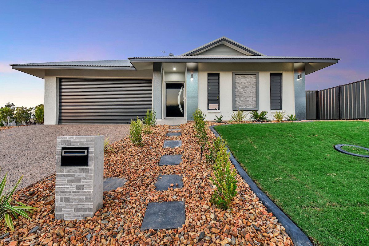 A white house with a black garage door is sitting on top of a lush green lawn.
