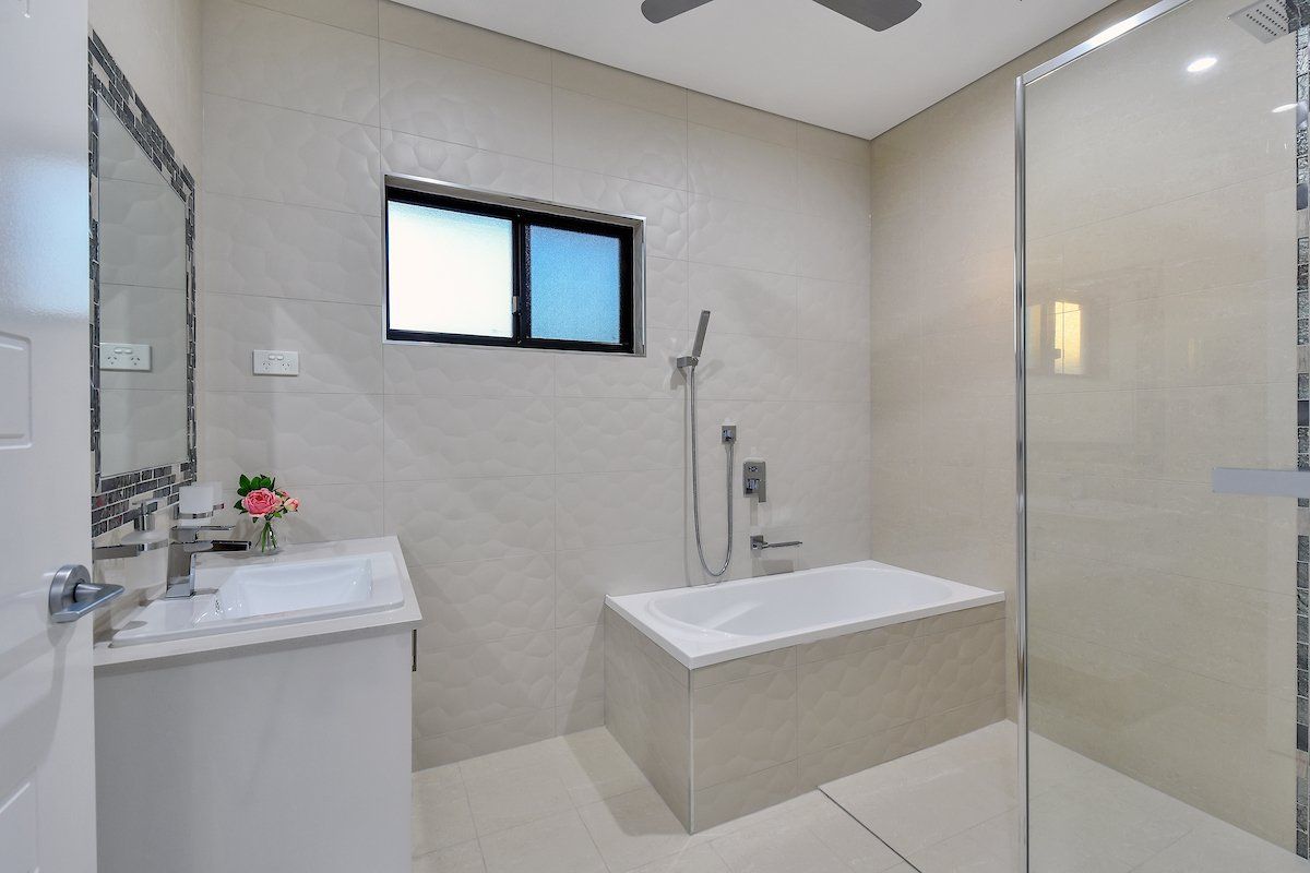 A bathroom with a tub , sink , mirror and shower.