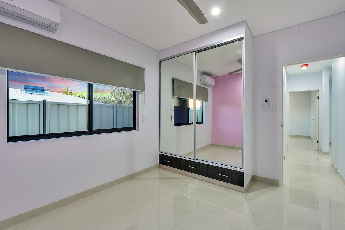 A bedroom with a large mirrored wardrobe and a ceiling fan