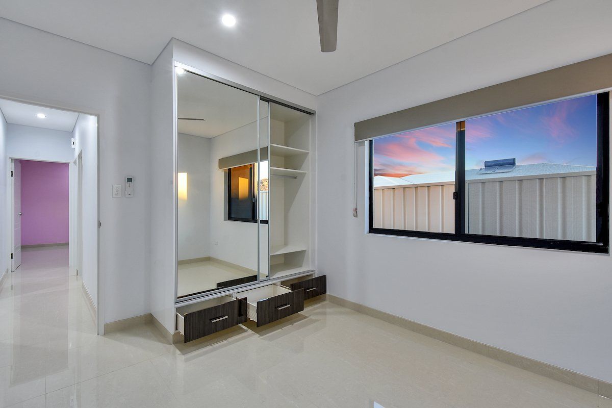 An empty bedroom with a large mirrored wardrobe and a window.